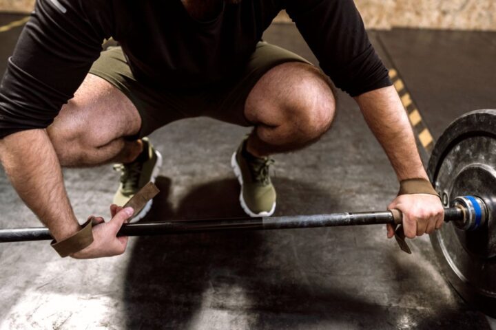 A man preparing to lift a barbell with weightlifting straps