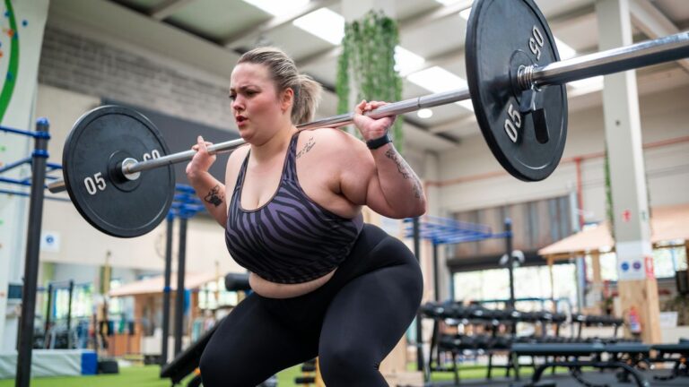 Woman performing a barbell squat at a gym