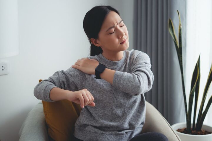 Woman holding her shoulder as she moves her arm