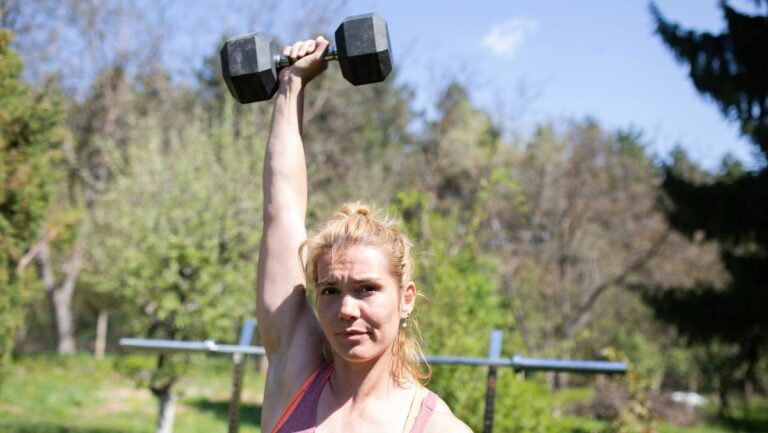 Woman holds dumbbell above her head