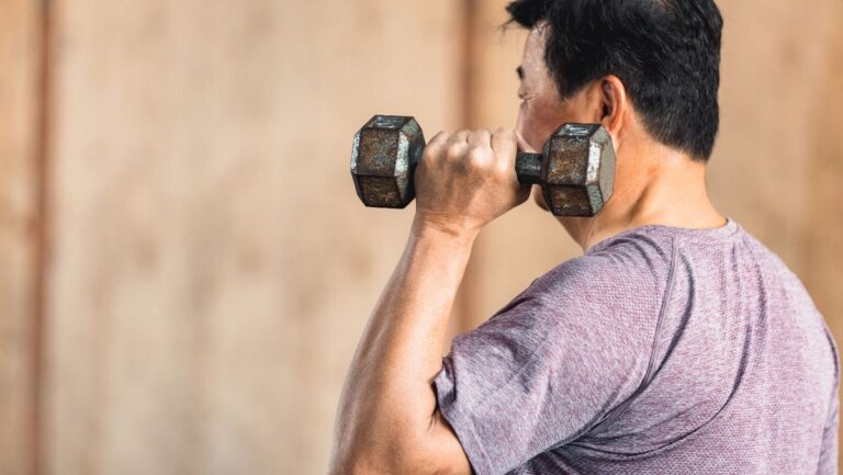 Man holding dumbbell by his shoulder