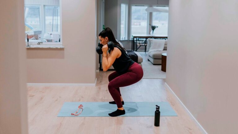 Woman performs dumbbell front squat at home