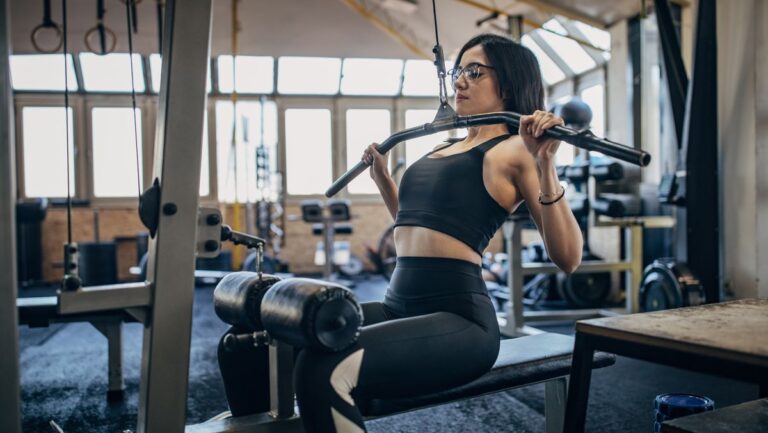 Woman performs the lat pull-down in a gym