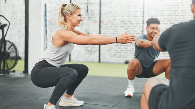 Woman squatting in a circle with other gym-goers