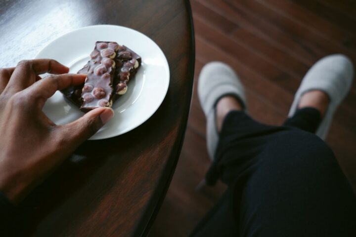 Hand picks up piece of chocolate from a plate