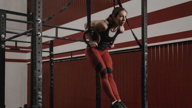 A woman performing a ring muscle-up in a CrossFit gym