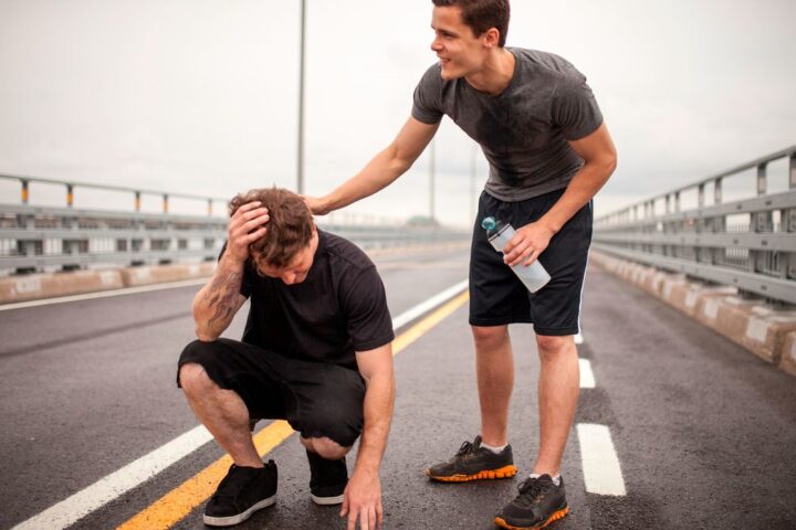 Man consoles runner crouched down with hand on head