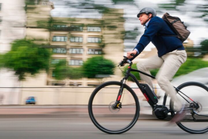 Man in casual business attire and bike helmet rides electric bike
